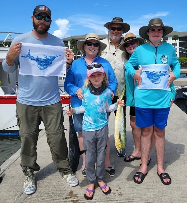 Family standing on boardwalk with Florida Offshore Fishing Company release flags