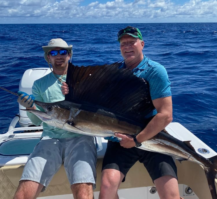 Large sailfish being held by charter guests
